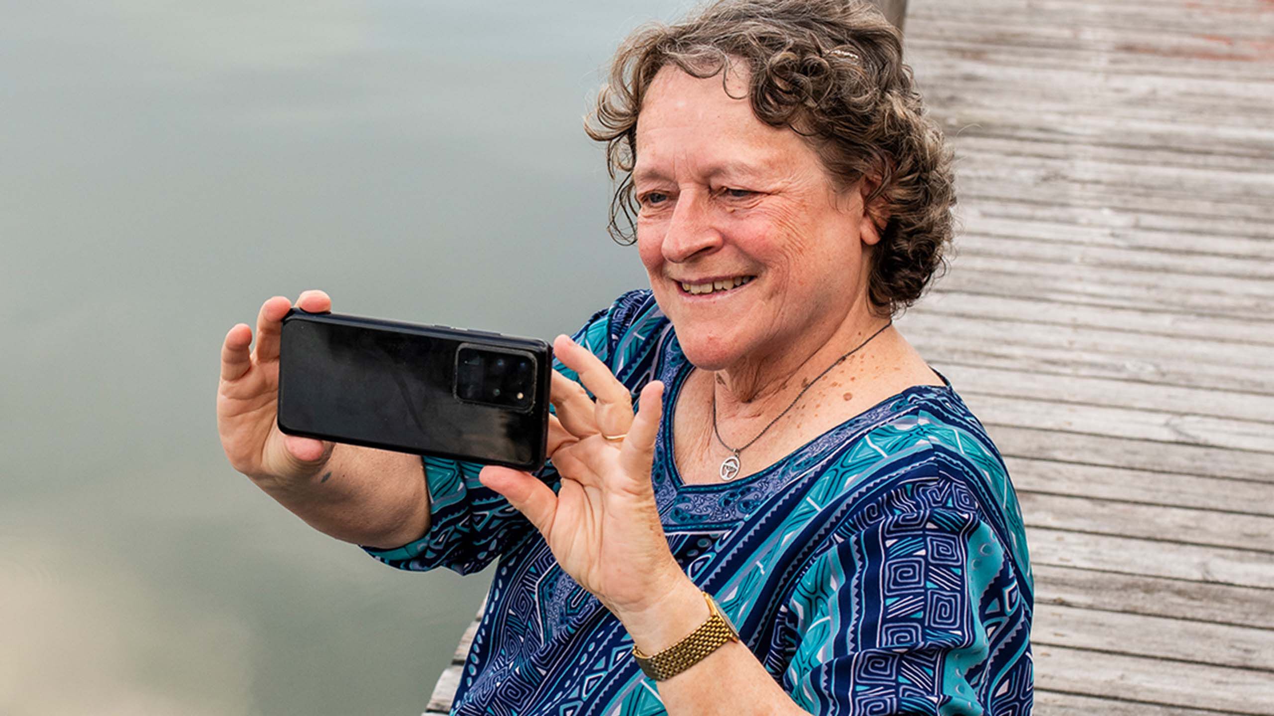 Kaihista eroon päässyt vanhempi rouva ulkona puhelimella kuvaten